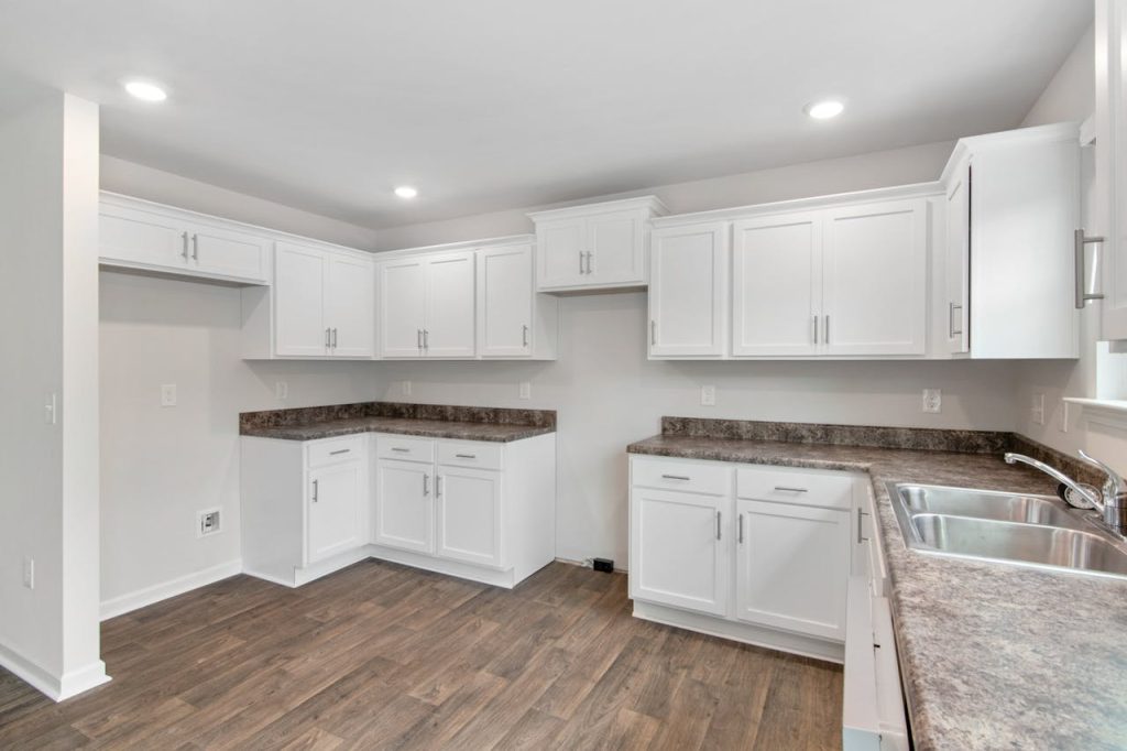 Spacious modern kitchen featuring white cabinetry, wooden floors, and natural lighting. Ideal for contemporary homes.